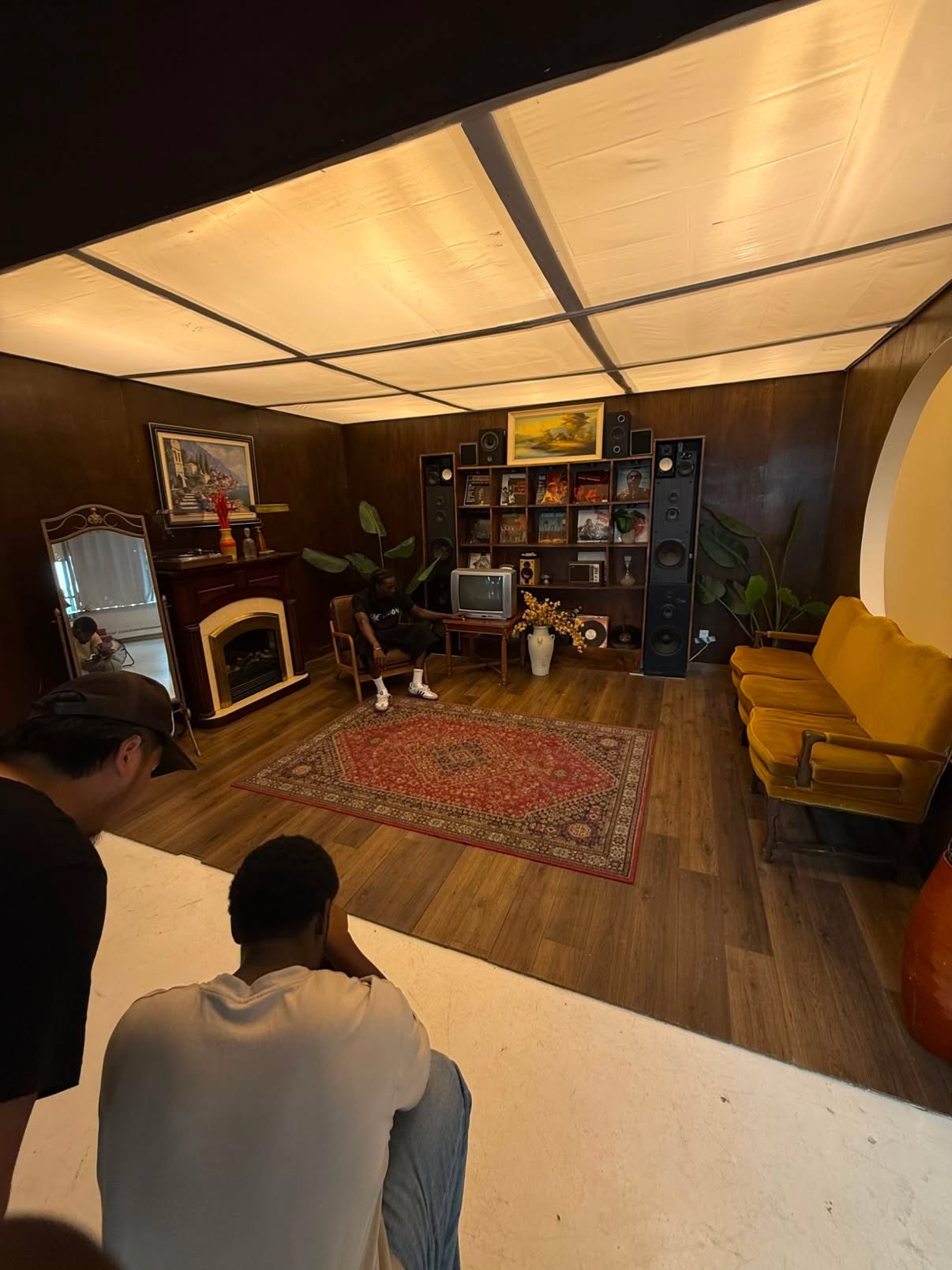 Wide shot of the hand-built listening room set with crew watching the take